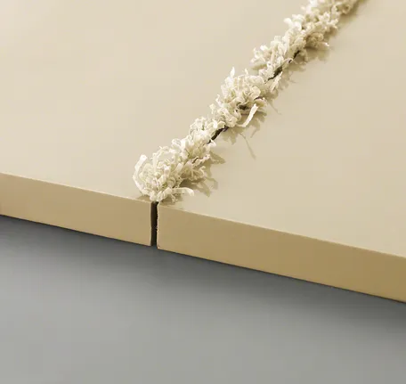 Two beige panels with a fresh groove cut and curled shavings along the edge.