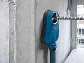 Drill dust extraction system attached to a concrete wall with an inserted drill bit.