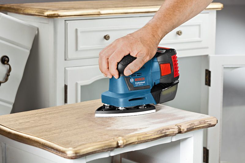 GSS 18V-10 A person operates a cordless orbital sander on a smooth surface.