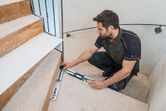 A person measures stair angles using an angle measurer on a staircase.
