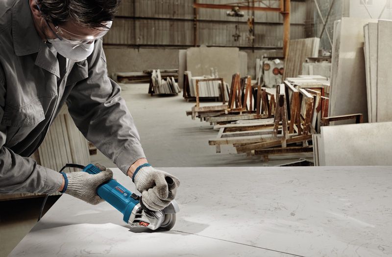 GWS 750 A person wearing safety equipment cuts a large marble slab with a power tool.