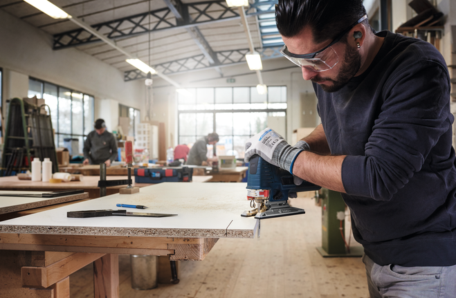 Jigsaw blade T 101 B Person wearing safety equipment uses a jigsaw to cut particle board in a workshop.
