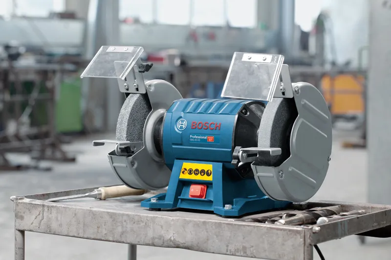 GBG 60-20 Double-wheeled bench grinder on a metal table in an industrial workshop.