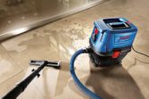 Wet/dry extractor vacuuming water from a tiled floor.
