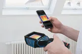 A person uses a thermo camera and smartphone to view a thermal image indoors.