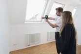 Person demonstrates a thermo camera to another person near a window in a bright room.