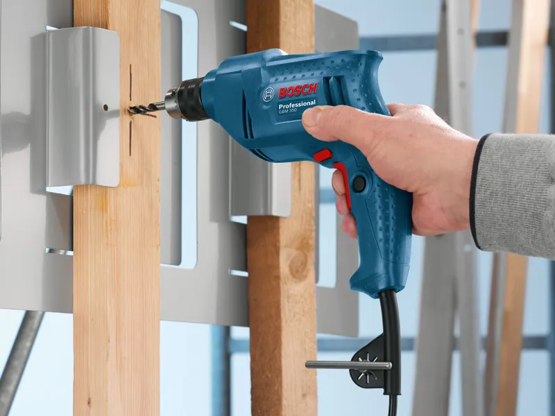 GBM 350 A person drills into a wooden beam mounted in a metal frame.