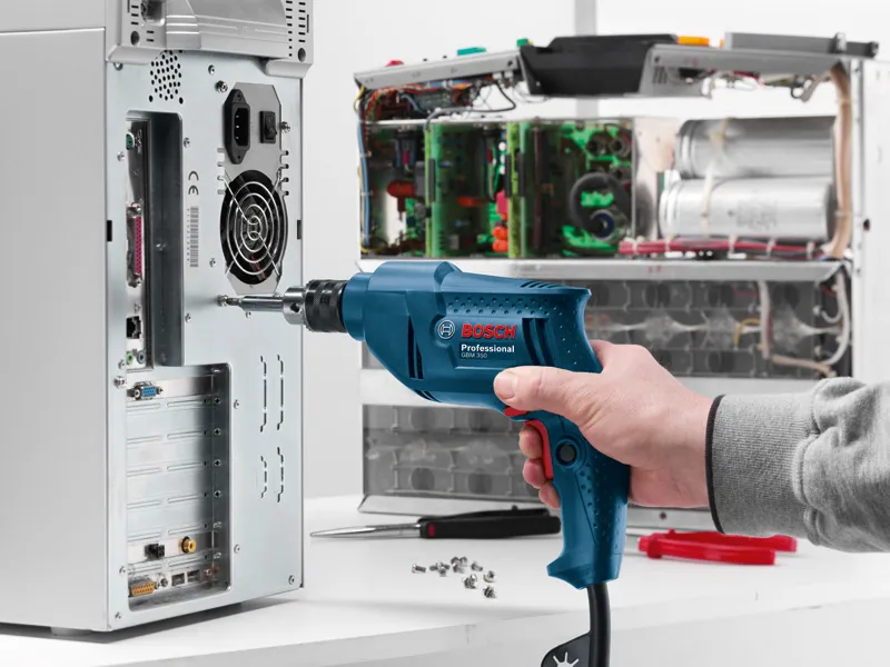 GBM 350 Person uses a drill to fasten a screw into an open computer case on a workbench.