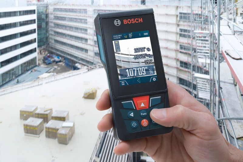 A person uses a laser measure on a building construction site.