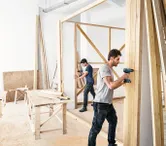 Two men building wooden wall.