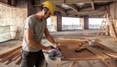 Worker sawing wooden board.