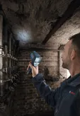 A person scans a damp ceiling in a basement with a thermo detector.