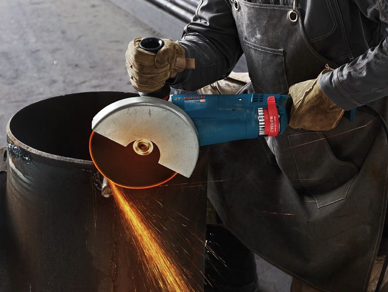 GWS 24-180 JZ A person wearing safety equipment cuts a metal pipe with an angle grinder.