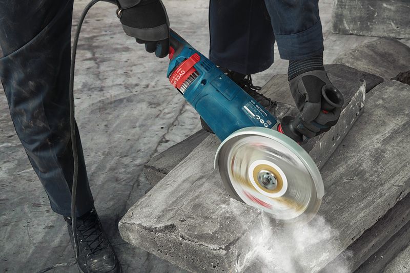 GWS 24-180 JZ A person wearing safety equipment uses a power cutter to cut a concrete block.