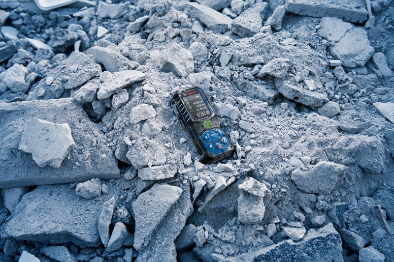Laser measure device resting on a pile of broken concrete rubble.