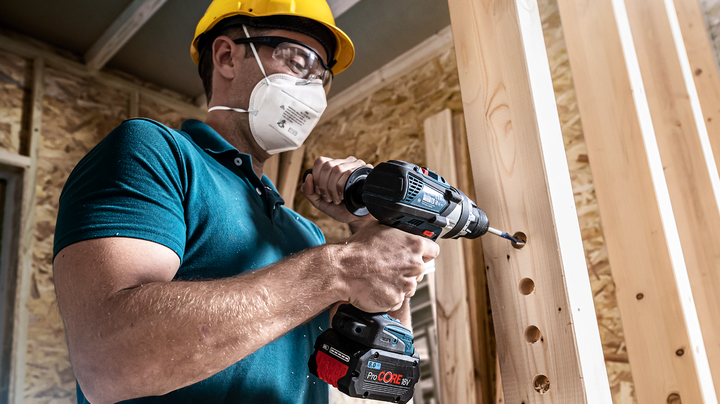 Object #200360551: 2793185_web_003 Worker wearing safety equipment drills holes into a vertical wooden beam.