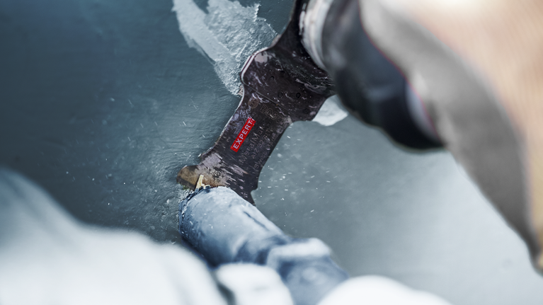 EXPERT MetalMax AIZ 32 AIT Multitool Blade 40 x 32 mm Person cutting through a painted metal pipe with a reciprocating saw blade.