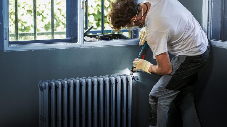 EXPERT MetalMax AIZ 32 AIT Multitool Blade 40 x 32 mm Person wearing safety equipment uses a cordless drill to install a radiator.