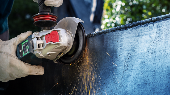 Object #200360613: 2793250_web_001 Person wearing safety equipment grinds a metal sheet with an angle grinder.