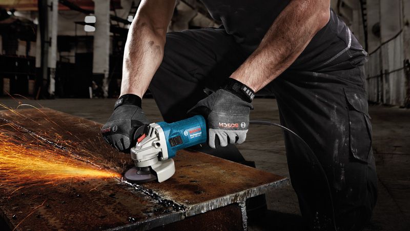 GWS 750 A person wearing safety equipment grinds metal, producing sparks on a workbench.