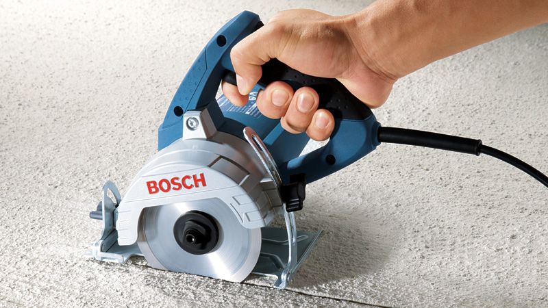 GDM 13-34 A person guides a marble saw cutting a straight line on a textured stone surface.