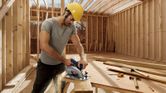 Man sawing wood construction.