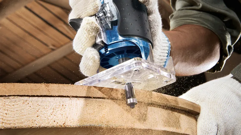 GKF 550 A person wearing safety equipment uses a palm router to shape the edge of a wooden board.