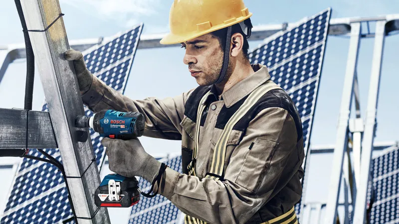 GDS 18V-400 A person wearing safety equipment uses a cordless impact wrench on a metal solar panel frame.