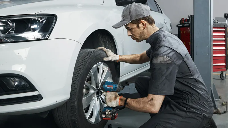 GDS 18V-400 A person wearing safety equipment uses a cordless impact wrench to tighten wheel bolts on a car.