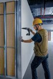 Worker drilling wall panel.