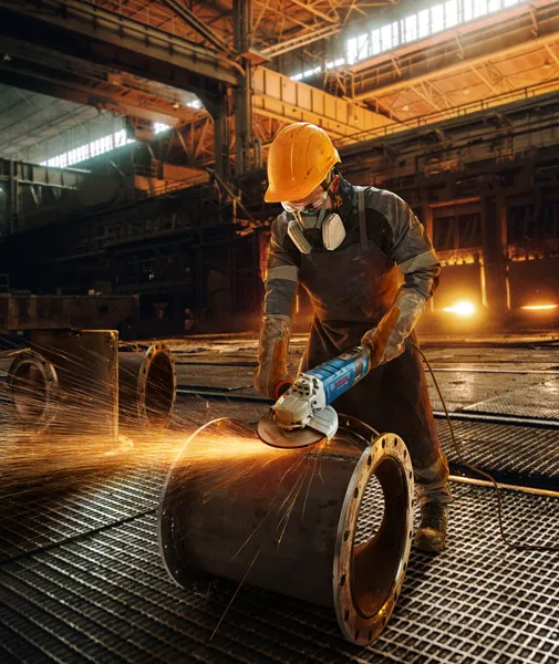 Worker grinding metal pipe.