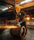 Worker grinding metal pipe.