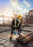 Person wearing safety equipment uses an angle grinder to cut steel rebar at a construction site.