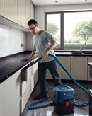 A person wearing safety equipment vacuums kitchen dust with a wet and dry extractor.