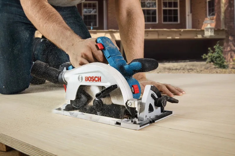 GKS 185-LI A person cuts wood with a cordless circular saw outdoors.