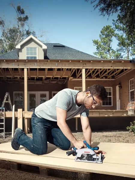 GKS 185-LI A person wearing safety equipment cuts wood on a construction site with a cordless circular saw.