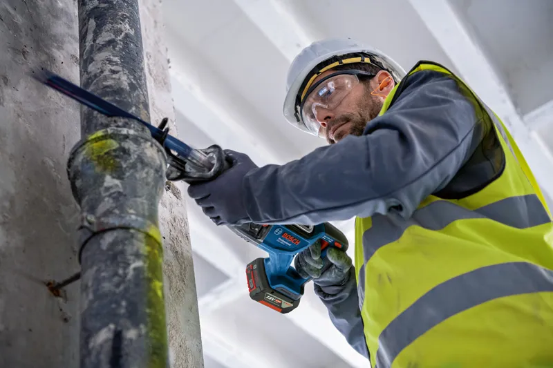 GSA 185-LI A person wearing safety equipment cuts a metal pipe with a reciprocating saw.