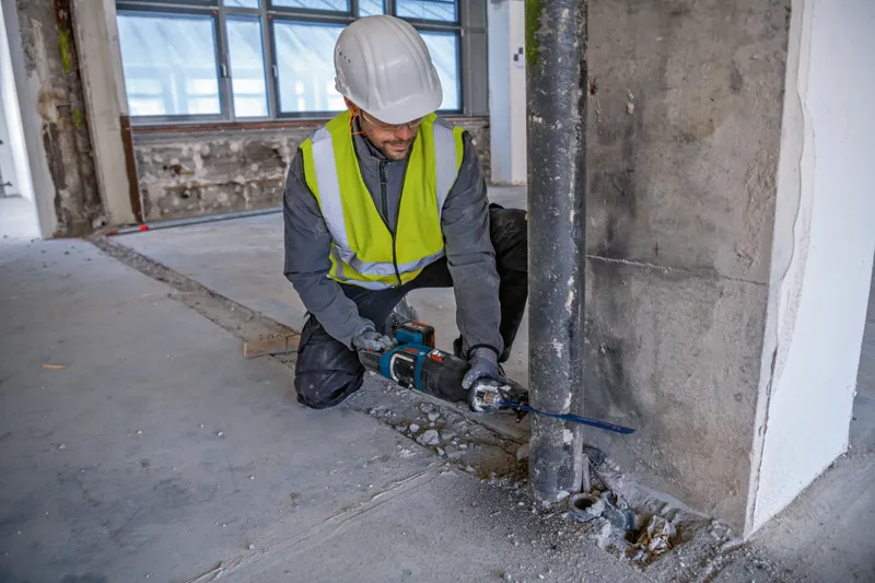 GSA 185-LI A person wearing safety equipment uses a reciprocating saw to cut a metal pipe.