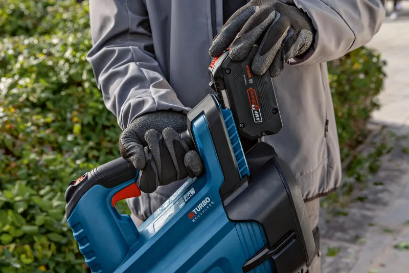 GBL 18V-750 A person wearing safety equipment inserts a battery into a cordless leaf blower.