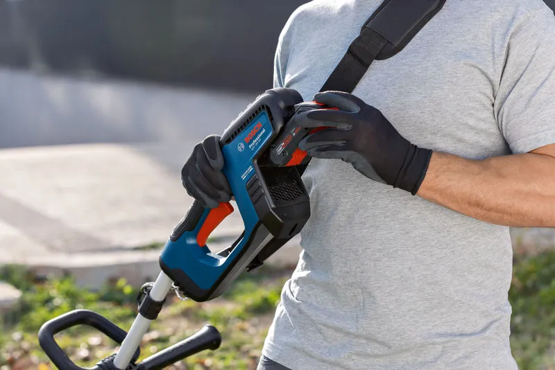 GRT 18V-33 A person wearing safety equipment attaches a battery to a cordless grass trimmer.