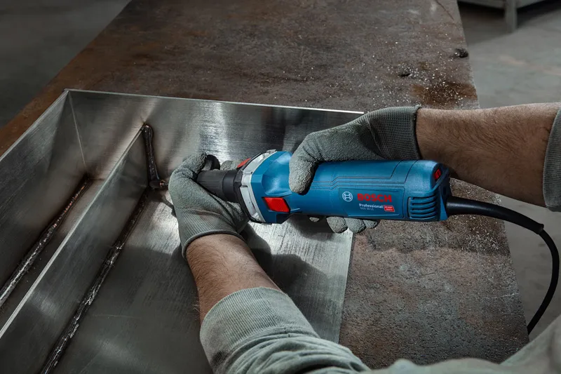 GGS 30 LS A person wearing safety equipment grinds a welded metal seam with a straight grinder.