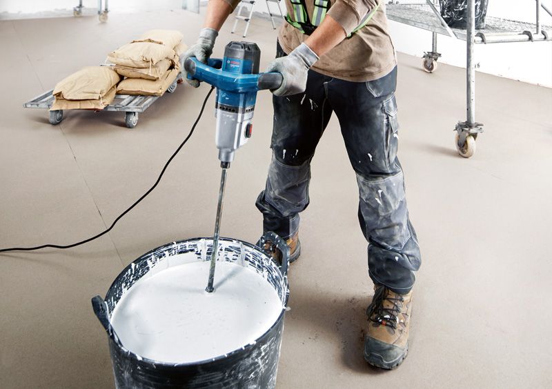 GRW 140 A person wearing safety equipment mixes paint with a powered stirring mechanism.