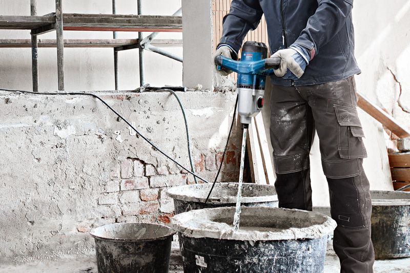 GRW 140 A person wearing safety equipment mixes construction material using a stirring mechanism.