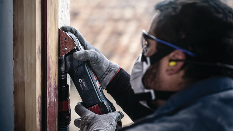 PRO F460 Sanding Sheet, 93 x 93 mm, G60, G80, G120, G180, G240, 10 pcs Person wearing safety equipment sands a wooden frame using a power tool.