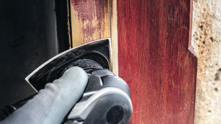 PRO F460 Sanding Sheet, 93 x 93 mm, G60, G80, G120, G180, G240, 10 pcs Person wearing safety equipment sands a wooden door frame with a power tool.