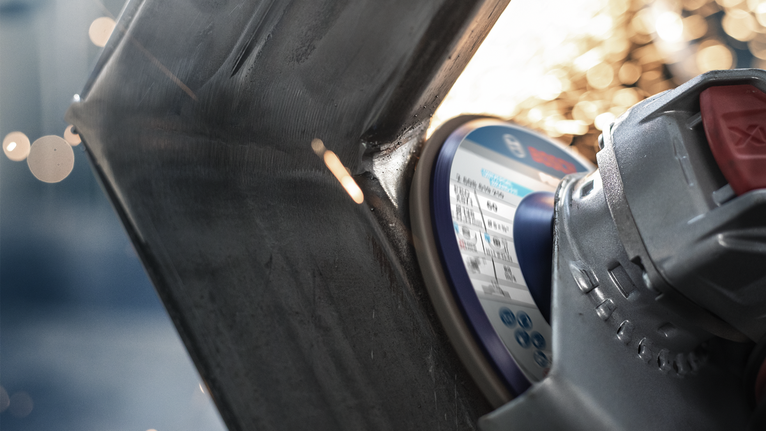 PRO X571 Flap Disc, Straight, 125 mm, G40, X-Lock Angle grinder cutting through metal, sparks flying from the point of contact.