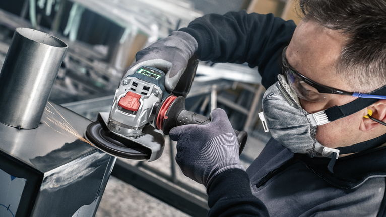 PRO R780 X-Lock Fibre Disc, 125 mm, G36 A person wearing safety equipment grinds metal with a power tool.