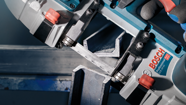 PRO CB281418 Band Saw Blade, 733 mm, 2 pcs Person wearing safety equipment uses a portable bandsaw to cut a metal beam.