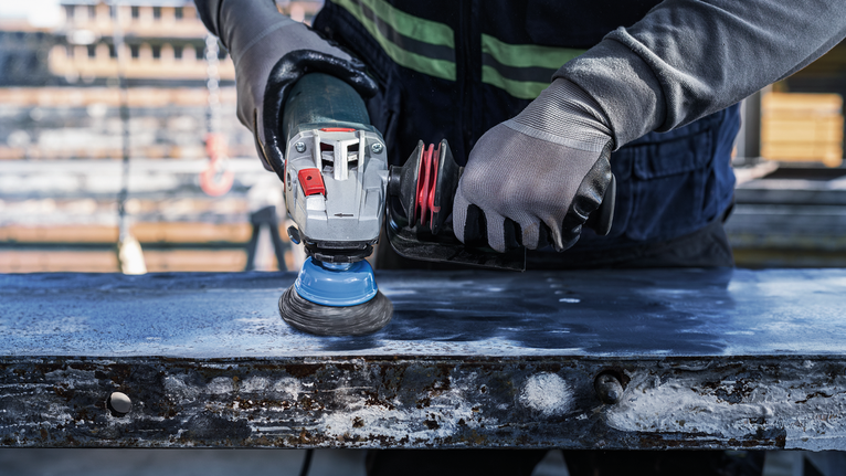 PRO Metal heavy Cup Brush, 75 x 0.5 mm, Thread Person wearing safety equipment polishes a metal surface with a power tool.