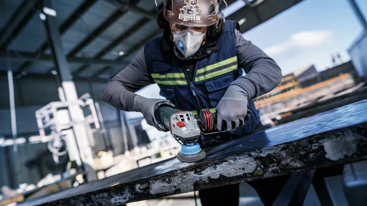 Object #200456909: 3089943_app_web_6 Person wearing safety equipment polishes a metal surface with an angle grinder.